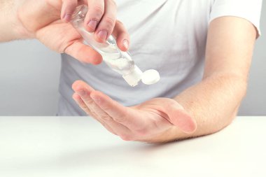 Küçük portatif antibakteriyel el dezenfektanı kullanan bir adam..