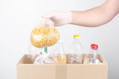 Eldivenli ve maskeli gönüllüler. Gri arka planda gıda malzemeleri olan bağış kutuları..