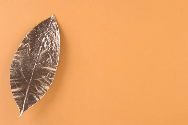 Leaves painted in gold on an orange background. Golden autumn concept.