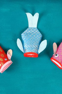 Mavi yeşil arka planda Diy koi sazan balığı. Çin yeni yılı için hediye fikirleri, dekor. Çocuk el yapımı. Sazan balığı kağıdı, tuvalet kağıdı, şaşı gözler. Adım adım. Çocuk işçiliğini işleyin. Üst görünüm.