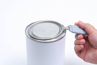Adamın biri beyaz arka planda konserve açacağı olan bir kavanoz beyaz boya açıyor. Yenileme