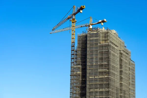 Gru a torre ponteggi costruzione grattacielo cielo blu — Foto Stock