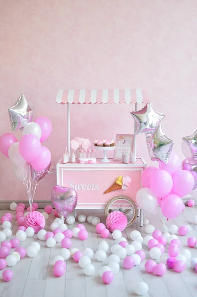 Decorations for birthday party. A lot of cakes. A lot of balloons red and white colors. One year birthday decorations. balloons pink and white colors. Ice cream party.