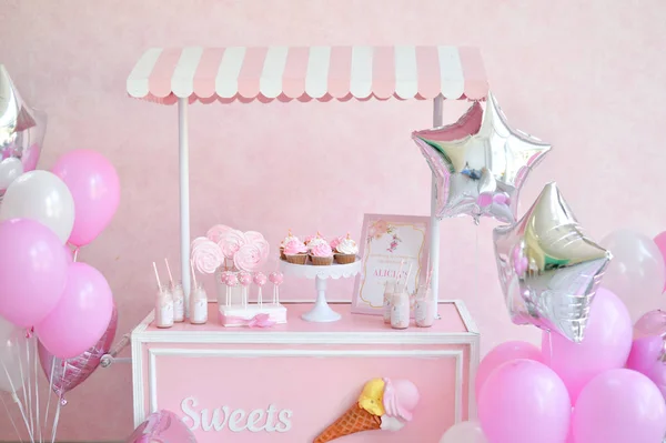 Decorations for birthday party. A lot of cakes. A lot of balloons red and white colors. One year birthday decorations. balloons pink and white colors. Ice cream party.
