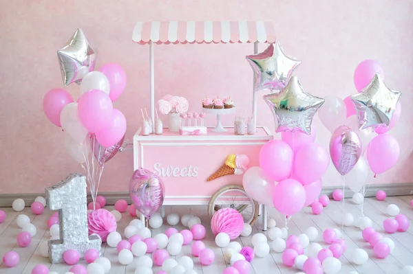 Decorations for birthday party. A lot of cakes. A lot of balloons red and white colors. One year birthday decorations. balloons pink and white colors. Ice cream party.