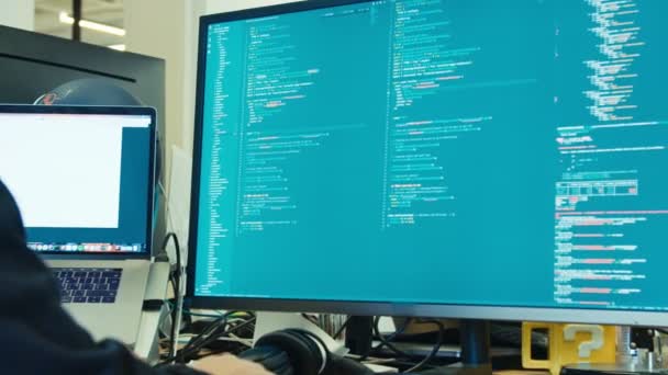 Programador de computadoras sentado frente a un software de codificación de pantalla — Vídeos de Stock