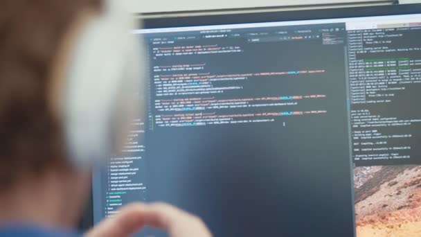 Computerprogrammeur zit achter een scherm codering software — Stockvideo