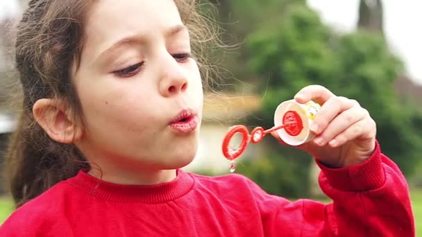 Schattig klein meisje blazen van zeepbellen in slow motion — Stockvideo