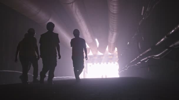 Silhouette of many construction workers walking out from a large tunnel — Stock Video