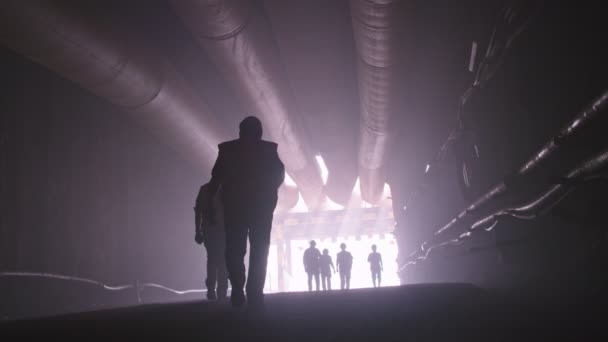 Silhouette of many construction workers walking out from a large tunnel — Stock Video