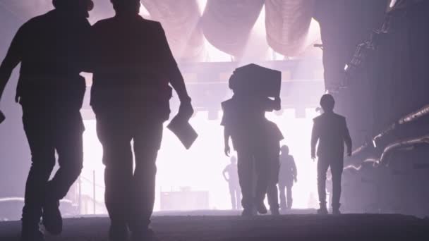 Silhouette of many construction workers walking out from a large tunnel — Stock Video