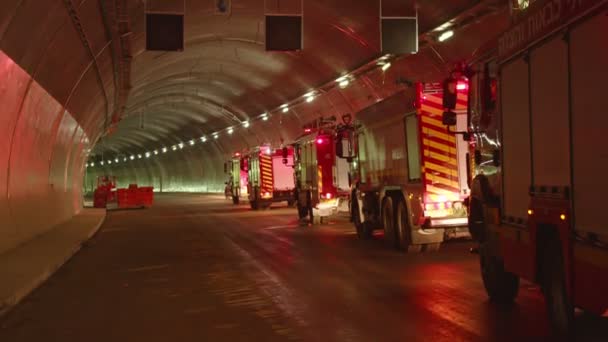 Camiones de bomberos entrando en un gran túnel con luces rojas para rescate — Vídeo de stock