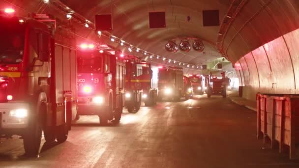 Camiones de bomberos entrando en un gran túnel con luces rojas para rescate — Vídeos de Stock