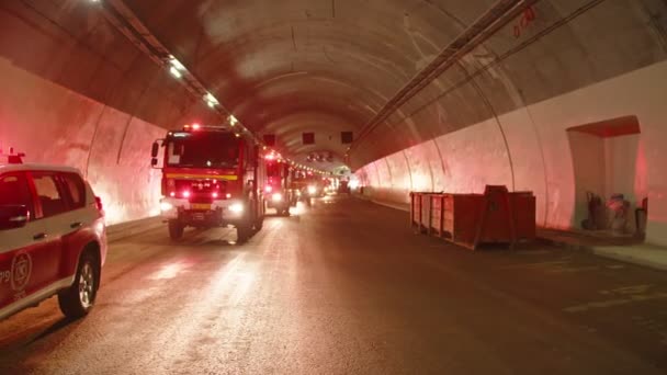 Camiones de bomberos entrando en un gran túnel con luces rojas para rescate — Vídeos de Stock