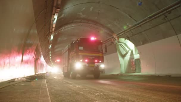 Camiones de bomberos entrando en un gran túnel con luces rojas para rescate — Vídeos de Stock