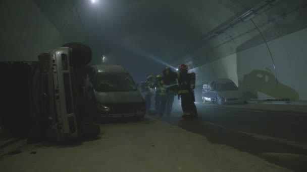 Escena de accidente de coche dentro de un túnel, bomberos rescatando a personas de los coches — Vídeo de stock