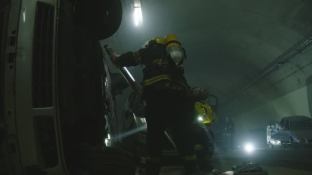 Scena di un incidente stradale all'interno di un tunnel, vigili del fuoco che salvano le persone dalle auto — Video Stock