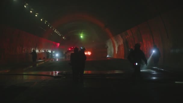 Brandweerlieden in een donkere tunnel met noodsituaties verlichting op de achtergrond — Stockvideo