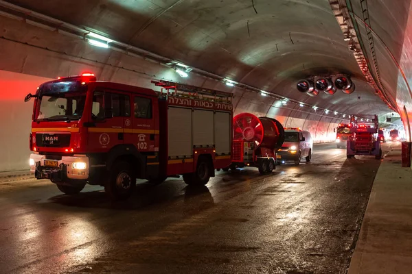 Caminhões de bombeiros que entram em um grande túnel com luzes vermelhas para resgate — Fotografia de Stock