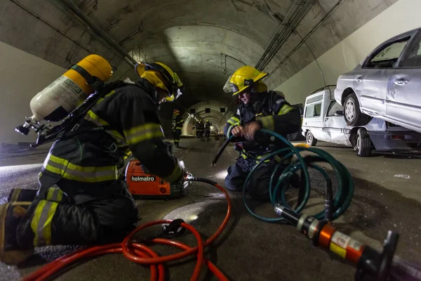 Car accident scene inside a tunnel, firefighters rescuing people from cars