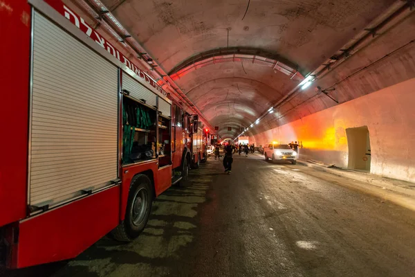 Caminhões de bombeiros que entram em um grande túnel com luzes vermelhas para resgate — Fotografia de Stock