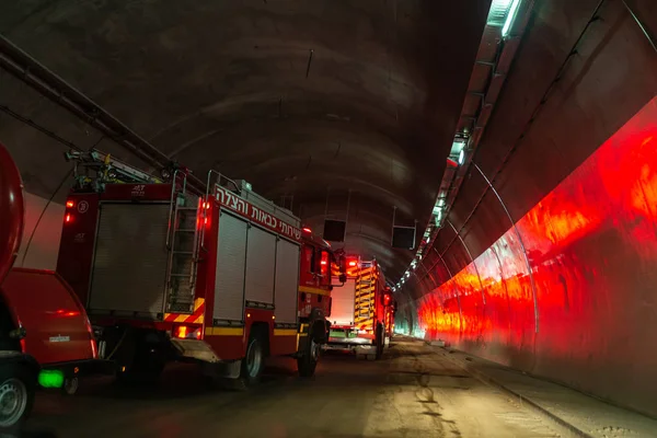 Fire trucks entering a large tunnel with red lights for rescue Stock Image