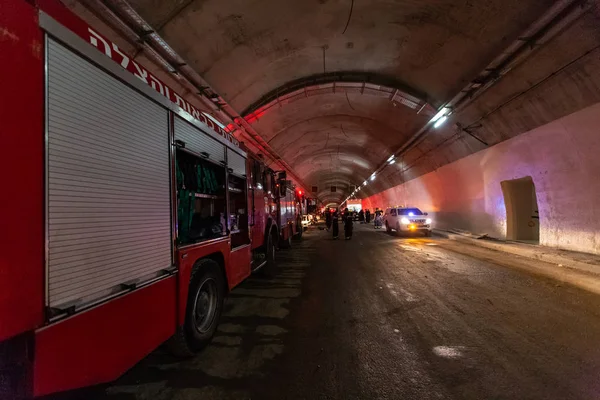 Truk pemadam kebakaran memasuki terowongan besar dengan lampu merah untuk penyelamatan Stok Foto