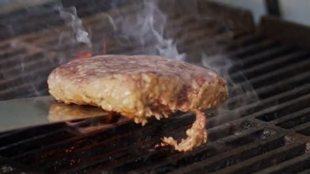 Movimento lento de hambúrguer de carne de vaca em uma grelha em close-up com chamas e fumaça — Vídeo de Stock