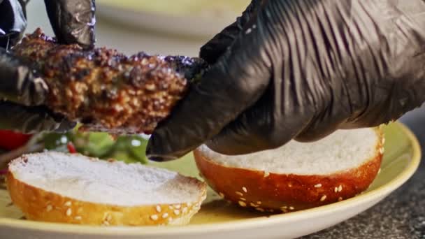 Αργή κίνηση του βοείου κρέατος χάμπουργκερ τοποθετείται σε ένα κουλούρι — Αρχείο Βίντεο