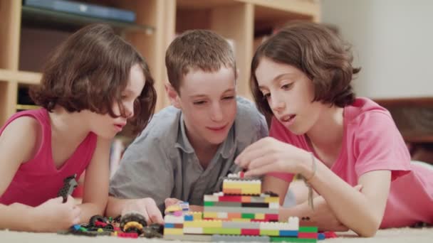 Tres niños jugando con ladrillos lego en casa — Vídeos de Stock