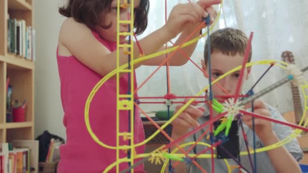 Niño y niña construyendo una torre de juguetes en casa — Vídeo de stock