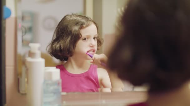 Niña cepillándose los dientes delante del espejo — Vídeo de stock