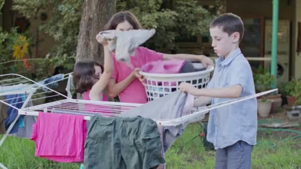 吊り線からバスケットに洗濯物を脱いで 3 人の子供 — ストック動画