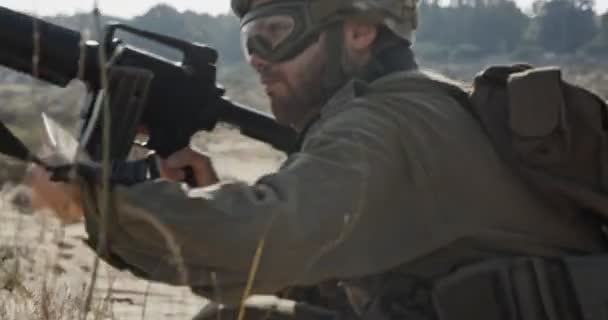 Солдат бежит по песчаному холму во время боя, под огнём — стоковое видео