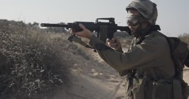 Ağır çekim bir tüfek ile bir kum tepe üzerinde yürüyen bir İsrail askeri — Stok video