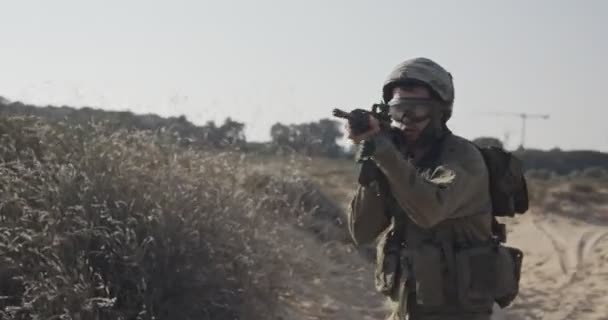 Movimento lento de um soldado israelita caminhando com uma espingarda em uma colina de areia — Vídeo de Stock