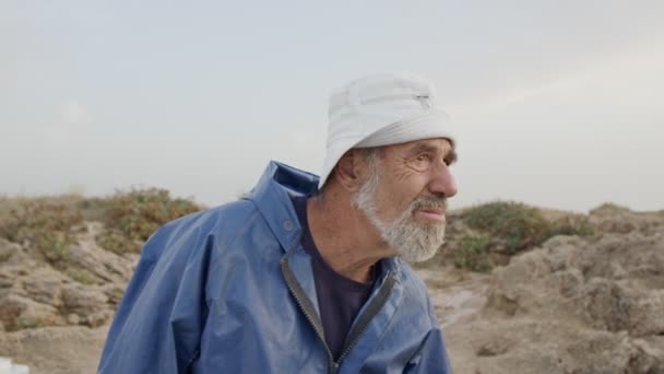 Старий рибалка дивиться в океан, використовуючи бінокль — стокове відео