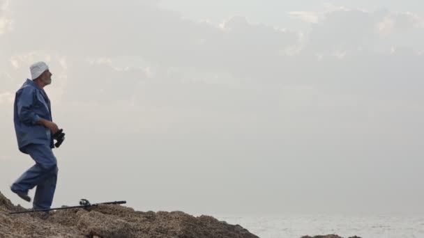 Old fisherman looking into the ocean using his binoculars — Stock Video