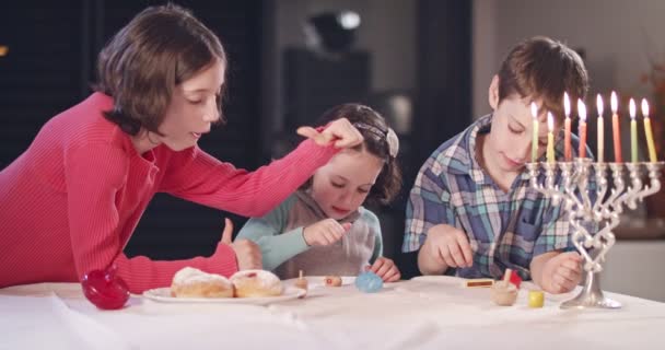 Kinderen spelen met dreidels tijdens Hanukka thuis — Stockvideo