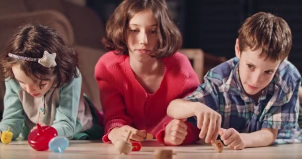 Kinderen spelen met dreidels tijdens Hanukka thuis — Stockvideo