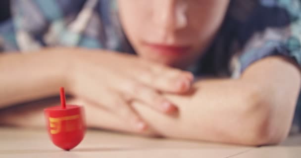 Primer plano de un chico haciendo girar un Hanukka dreidel en el suelo — Vídeo de stock