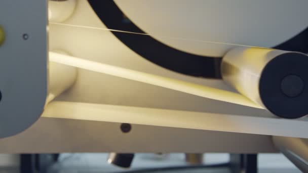 Closeup sobre papel que se move através de uma grande máquina de impressão industrial — Vídeo de Stock