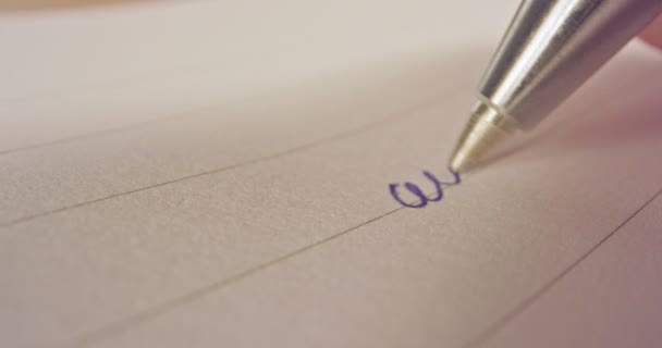 Скользящий макро-снимок кончика пера, пишущего французские слова на бумаге — стоковое видео