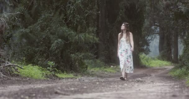 Jonge mooie vrouw met een witte jurk wandelen in een groen bos — Stockvideo