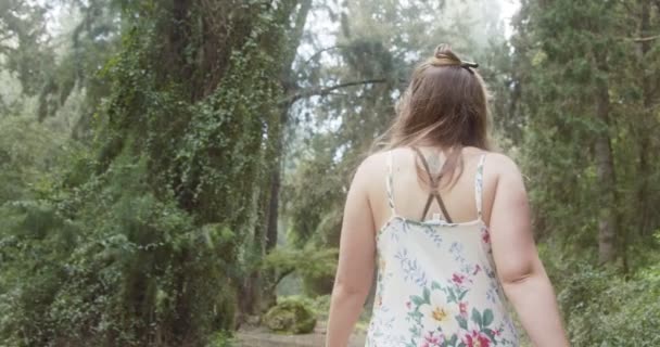 Joven hermosa mujer con un vestido blanco caminando en un bosque verde — Vídeos de Stock