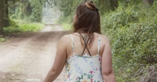 Joven hermosa mujer con un vestido blanco caminando en un bosque verde — Vídeo de stock