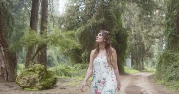 Joven hermosa mujer con un vestido blanco caminando en un bosque verde — Vídeo de stock