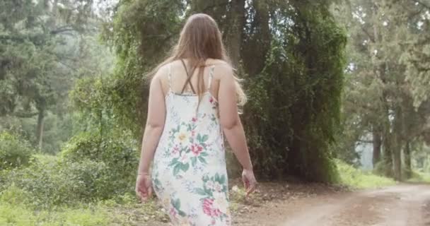 Νεαρή όμορφη γυναίκα με ένα λευκό φόρεμα που περπατάει σε ένα καταπράσινο δάσος — Αρχείο Βίντεο
