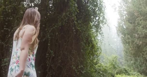 Joven hermosa mujer con un vestido blanco caminando en un bosque verde — Vídeos de Stock