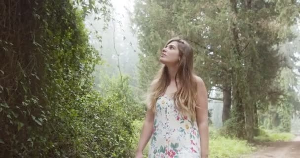 Ung, vakker kvinne med hvit kjole som går i grønn skog – stockvideo